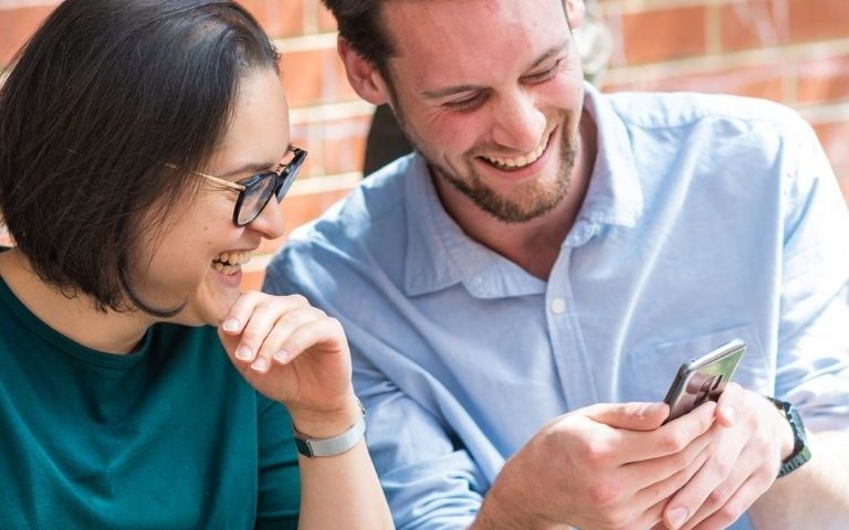 man and women looking at a mobile phone and laughing